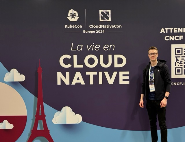 Me standing in front of a KubeCon sign.
